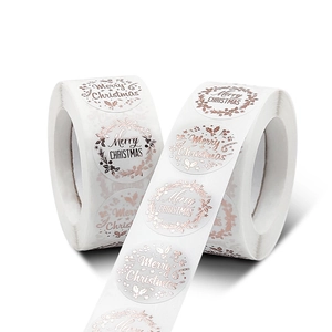 Two rolls of white Merry Christmas stickers with rose gold foil and festive patterns