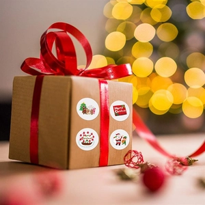 Merry Christmas round stickers on kraft gift box with red silk ribbon and bokeh lights