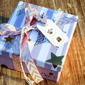 Close-up of decorative Christmas stickers on a gift box with a reindeer clip