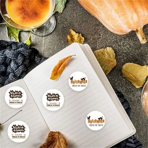 Halloween pumpkin and black cat round stickers on a notebook with cozy autumn decor