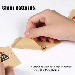 Close-up of hand peeling a Merry Christmas kraft paper sticker with To and From fields