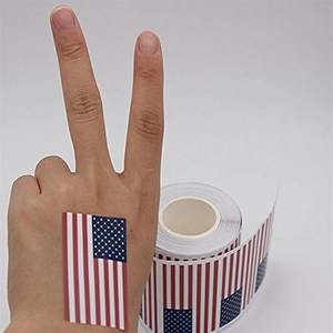 Roll of 250 American flag patriotic stickers applied on hand for size reference