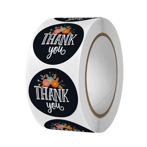 Close-up of a roll of black floral thank you stickers for gift sealing and packaging