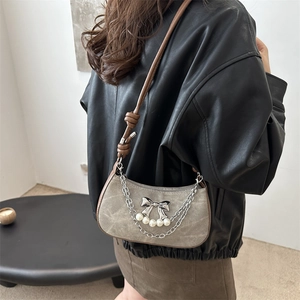 Vintage style shoulder bag with pearl butterfly charm and chain detail on black jacket