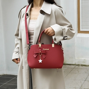 Red lychee pattern handbag with bow decor and gold chain strap shown on model
