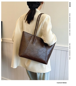Deep brown large tote bag with retro wrinkled texture styled on model's shoulder