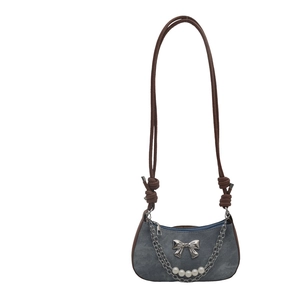 Sac sous le bras en denim avec nœud argenté et chaîne de perles sur fond blanc