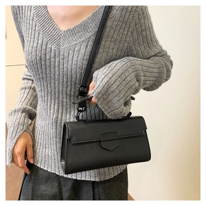 Close-up of black crossbody bag with cross-grain leather texture and metallic buckle