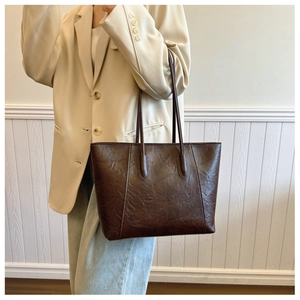 Detailed texture of retro dark brown leather tote bag on model for casual commuting