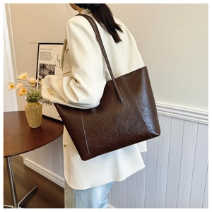 Macro shot of large dark brown leather tote bag texture with minimalist stitching