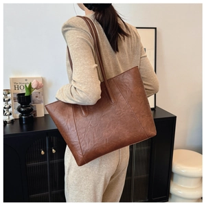 Close-up of vintage brown leather tote bag with distressed texture and slim straps