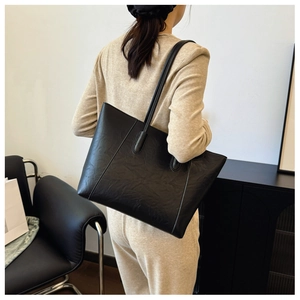 Close-up of black retro textured tote bag with pleated leather and long shoulder straps