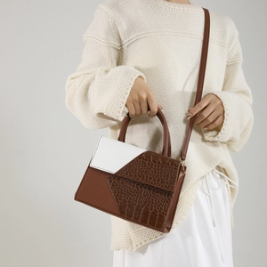 Sac à main élégant patchwork texture crocodile avec bandoulière porté par un mannequin