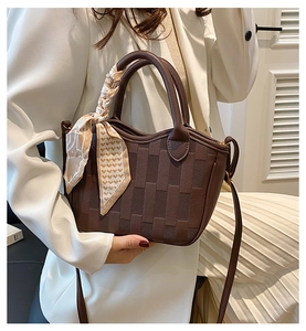 Close-up of brown woven bucket bag with silk scarf detail and golden hardware
