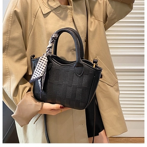 Detail of black lychee grain bucket bag with checkered embossing and silk scarf handle