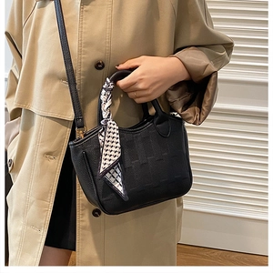 Detail of black lychee grain leather bucket bag with decorative silk scarf on handle