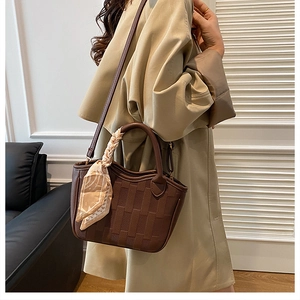 Detail of dark brown woven bucket bag with silk scarf on a model for casual style