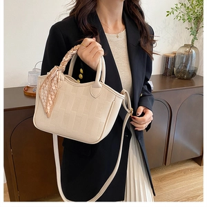 Detail of beige litchi grain leather bucket bag with silk scarf handle and adjustable strap