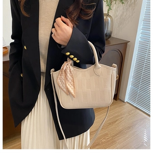 Chic beige bucket bag with decorative silk scarf and leather texture shown on model