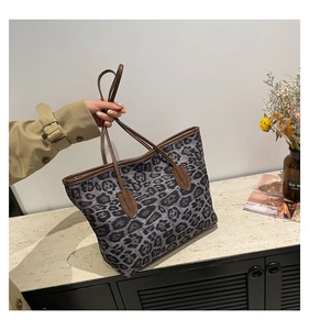 Detail of leopard print tote bag featuring brown leather handles and a spacious canvas design