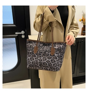 Close-up of leopard print tote bag detailing brown leather straps and stitching