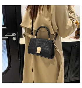 Dettaglio borsa a tracolla nera su trench beige con patta glitterata e pelle liscia