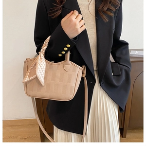 Detail of apricot checkered bucket bag with elegant silk scarf and leather shoulder strap
