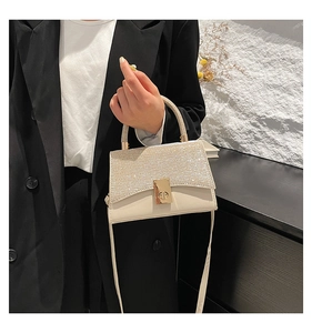 Detail of cream PU mini bag featuring a glittery flap and golden metallic twist lock