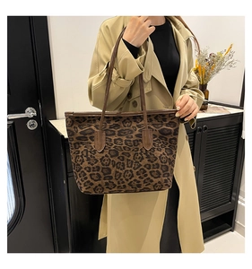 Close-up of leopard print tote bag with brown leather handles worn with a beige trench coat