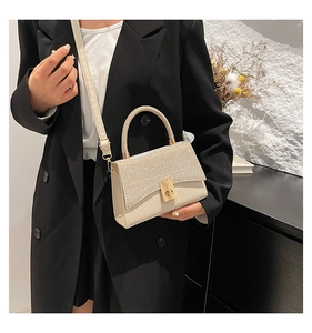Detail of cream PU mini bag with sparkling rhinestones and golden trapezoid twist lock