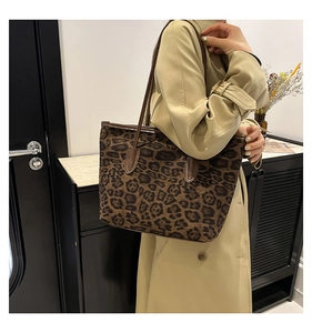 Detail of leopard print tote bag with brown leather shoulder straps and trim