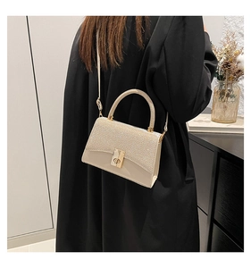 Vista dettagliata della borsa quadrata bianco crema con trama glitterata e chiusura dorata
