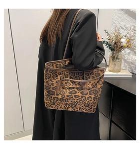 Detail of a large leopard print tote bag with slim shoulder straps on a black coat