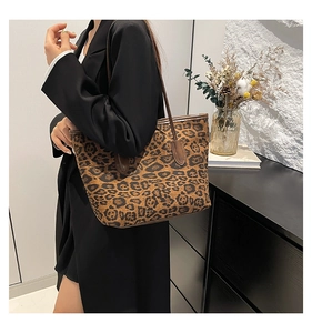 Detailed view of the large leopard print tote bag featuring sturdy brown leather handles