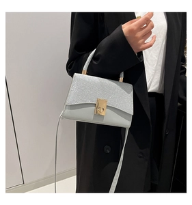 Detail of grey mini square bag with glitter flap and golden metallic twist lock closure