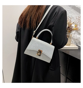Mini borsa a tracolla argento glitterata indossata da un modello in un interno moderno