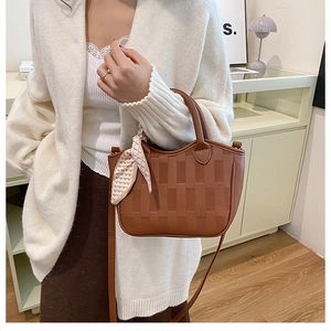 Detail of brown lychee leather bucket bag with embossed texture and heart pattern scarf