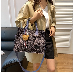 Detail of leopard print canvas tote bag featuring purple straps and a plush bear charm