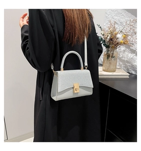 Detail of silver sequin square bag with gold twist lock and slim shoulder strap