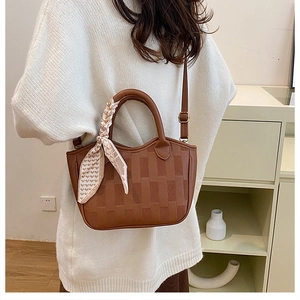 Brown leather bucket bag with checkered embossing and silk scarf on crossbody model