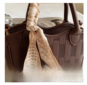 Detail of dark brown woven bucket bag featuring a silk scarf wrapped around the handle