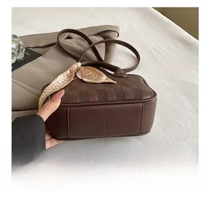 Detail showing high-quality lychee grain leather bottom of a dark brown bucket handbag