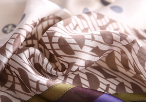Macro détaillée montrant la texture soyeuse et les motifs géométriques rétro sur le foulard