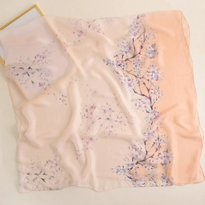 Détail d'une écharpe en soie dégradé rose avec imprimé cerisier et drapé élégant