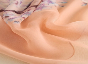 Gros plan sur le tissu d'écharpe en soie florale rose pêche avec une texture délicate