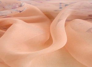 Gros plan d'un foulard pêche transparent avec motifs floraux violets et texture fine