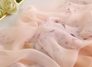 Détail du tissu mousseline à motif floral rose pâle avec plis et drapés translucides