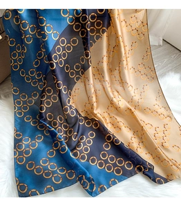 Close-up of silk scarf with vintage gold chain print and geometric color blocks