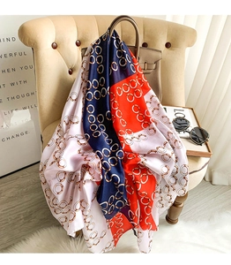 Detail of silk scarf with geometric ring print draped over a luxury chair and bag