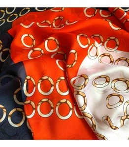 Close-up of silk scarf with orange and navy block patterns and golden chain prints